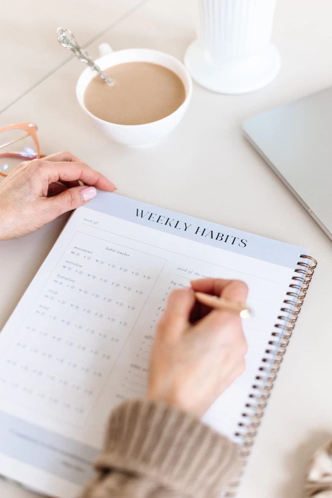 Filling in the Weekly Habits page of the Fraîche Start workbook beside a cup of coffee